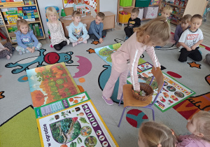 dzieci siedza na dywanie, na środku ilustracje sadu i ogrodu