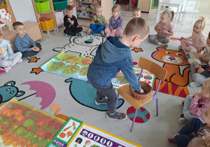 dzieci siedza na dywanie, na środku ilustracje sadu i ogrodu