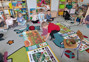 dzieci siedza na dywanie, na środku ilustracje sadu i ogrodu