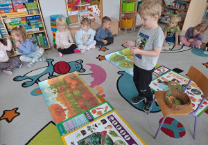 dzieci siedza na dywanie, na środku ilustracje sadu i ogrodu