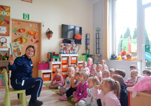 Pani policjantka czyta dzieciom bajeczkę o numerach alarmowych.