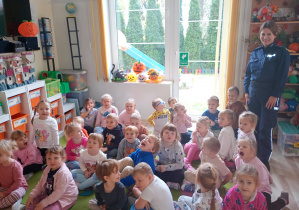 Dzieci pozują do zdjęcia w sali z Panią policjantką.