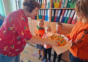 Trójka dzieci z grupy „Pszczółki” częstuje pomarańczą