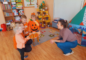 Trójka dzieci z grupy „Pszczółki” częstuje pomarańczą