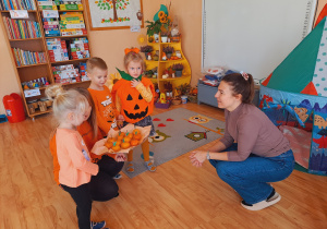 Trójka dzieci z grupy „Pszczółki” częstuje pomarańczą