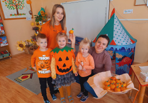 Trójka dzieci z grupy „Pszczółki” częstuje pomarańczą
