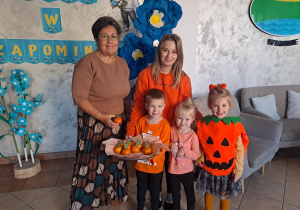 Trójka dzieci z grupy „Pszczółki” częstuje pomarańczą