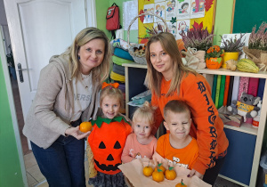 Trójka dzieci z grupy „Pszczółki” częstuje pomarańczą