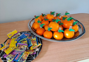 Trójka dzieci z grupy „Pszczółki” częstuje pomarańczą