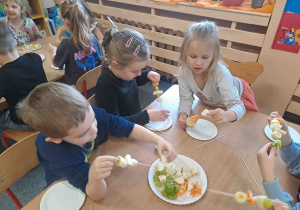 Dzieci wykonują szaszłyki z owoców