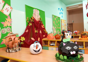 Prace wykonane z dyń ustawione na półkach w szatni przedszkola.