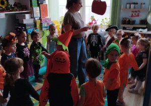 Dzieci uczestniczą w zabawie tanecznej prowadzonej przez nauczycielkę w sali.