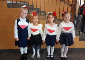 Dziewczynki pozują do zdjęcia w galowych strojach.