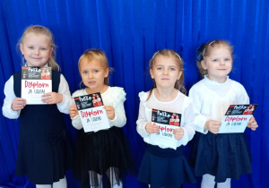 Dziewczynki pozują do zdjęcia z pamiątkowymi dyplomami.