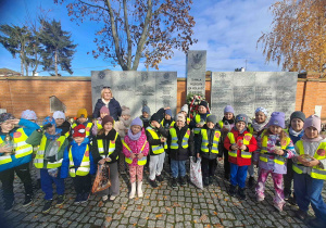 Dzieci na cmentarzu przed tablicą upamiętniającą poległych w walkach o wolność i niepodległość