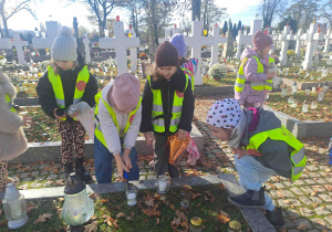 Dzieci zapalają lampki na grobach żołnierzy