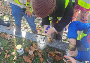 Dzieci zapalają lampki na grobach żołnierzy