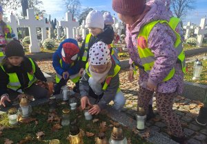 Dzieci zapalają lampki na grobach żołnierzy