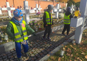 Dzieci zapalają lampki na grobach żołnierzy