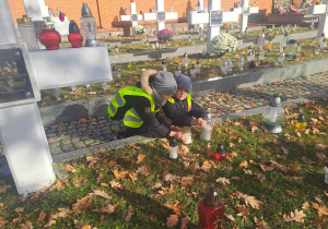 Dzieci zapalają lampki na grobach żołnierzy