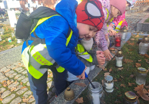 Dzieci zapalają lampki na grobach żołnierzy
