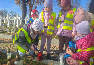Dzieci zapalają lampki na grobach żołnierzy
