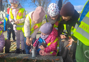 Dzieci zapalają lampki na grobach żołnierzy