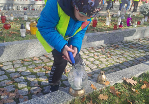 Dzieci zapalają lampki na grobach żołnierzy