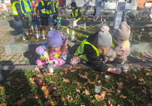 Dzieci zapalają lampki na grobach żołnierzy