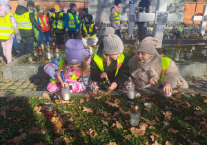 Dzieci zapalają lampki na grobach żołnierzy