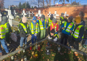 Dzieci zapalają lampki na grobach żołnierzy