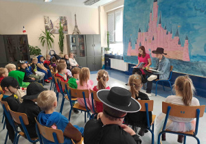 Dzieci słuchają bajek czytanych przez licealistów