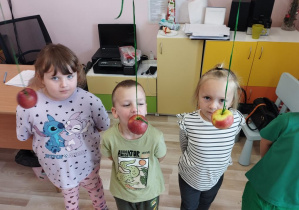 Dzieci próbują zjeść jabłko bez użycia rąk