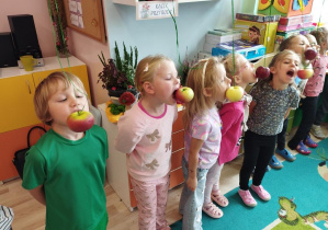 Dzieci próbują zjeść jabłko bez użycia rąk