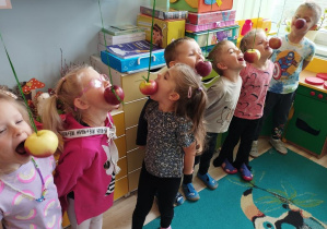 Dzieci próbują zjeść jabłko bez użycia rąk