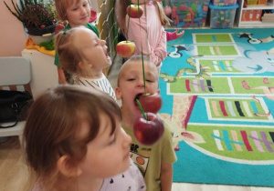 Dzieci próbują zjeść jabłko bez użycia rąk