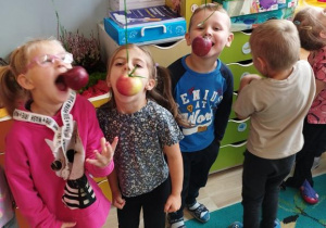 Dzieci próbują zjeść jabłko bez użycia rąk