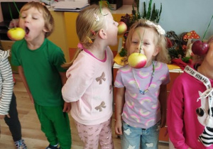 Dzieci próbują zjeść jabłko bez użycia rąk