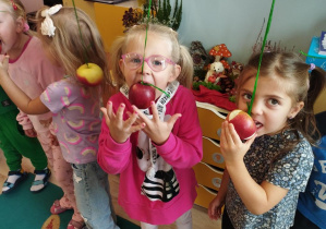 Dzieci próbują zjeść jabłko bez użycia rąk