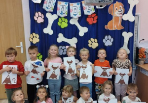 Dzieci pozują na tle pięknej dekoracji ze swoją pracą plastyczną