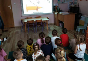 Dzieci siedzą i oglądają film edukacyjny o psach