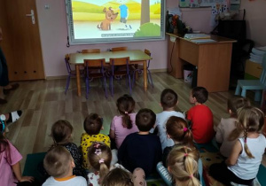 Dzieci siedzą i oglądają film edukacyjny o psach