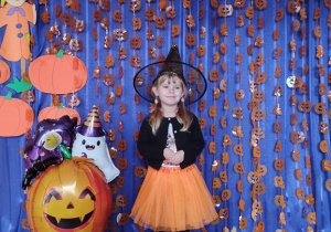 Dziecko pozuje na tle dyniowej dekoracji