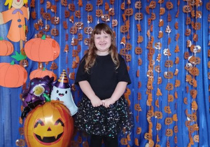 Dziecko pozuje na tle dyniowej dekoracji