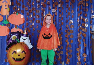 Dziecko pozuje na tle dyniowej dekoracji