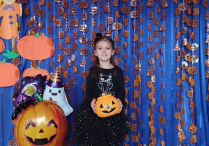 Dziecko pozuje na tle dyniowej dekoracji