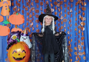 Dziecko pozuje na tle dyniowej dekoracji