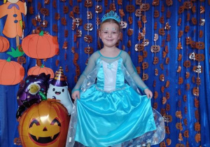 Dziecko pozuje na tle dyniowej dekoracji