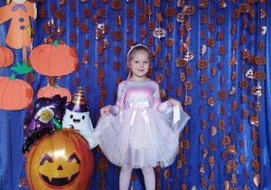 Dziecko pozuje na tle dyniowej dekoracji