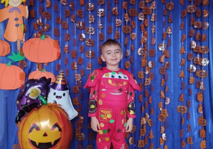 Dziecko pozuje na tle dyniowej dekoracji